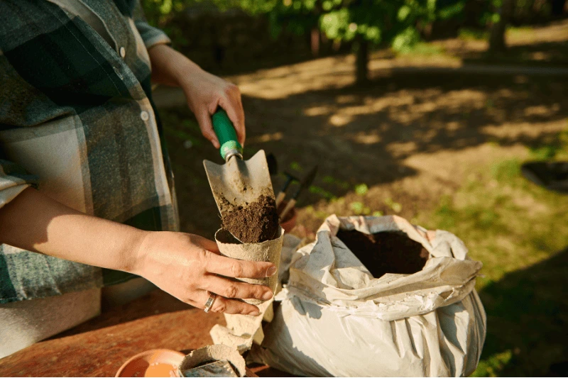 Hands mixing soil and adding fertilizer, demonstrating essential practices for caring for vertical gardens and ensuring proper plant nutrition.