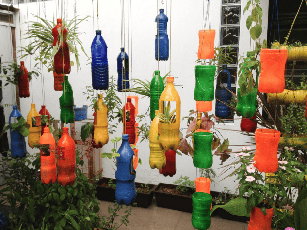 Colorful painted PET bottles repurposed as planters, adding vibrant design elements to sustainable vertical gardens.