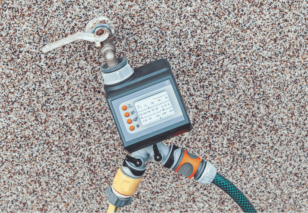 Timer connected to an automated irrigation system, used to schedule watering for plants in a vertical garden.
